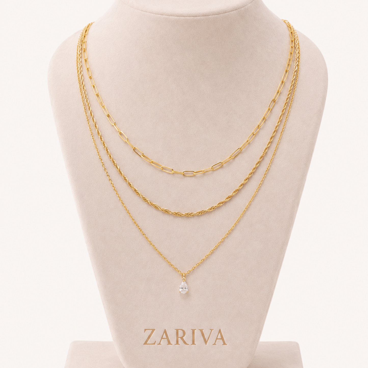 Crystal cascade necklace with layered gold chains and a clear teardrop charm displayed on a ZARIVA jewellery bust.