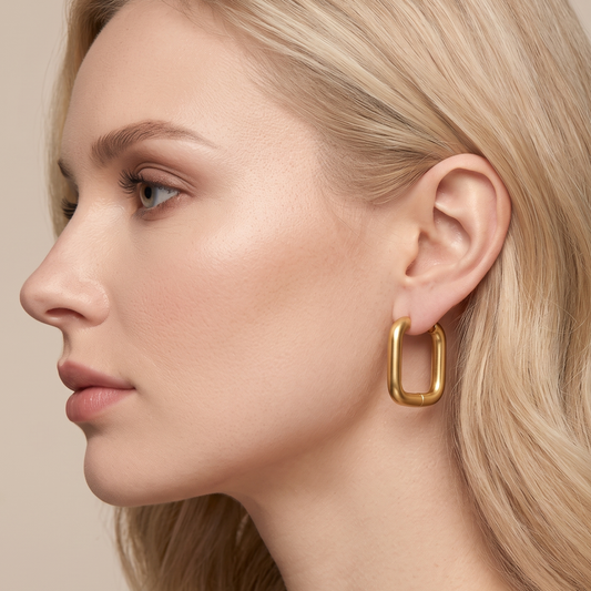 Gold square hoop earrings worn on the ear, showcasing a smooth rounded geometric silhouette for an elegant contemporary look by ZARIVA.
