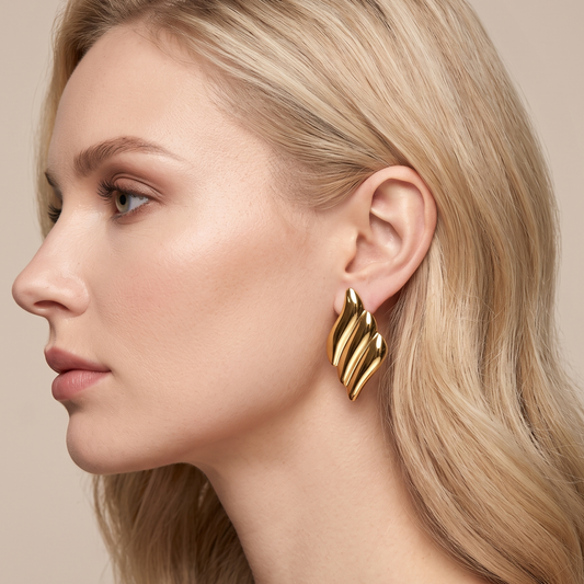 Gold statement earrings with sculptural curves worn on the ear, showing their elegant contemporary design by ZARIVA.