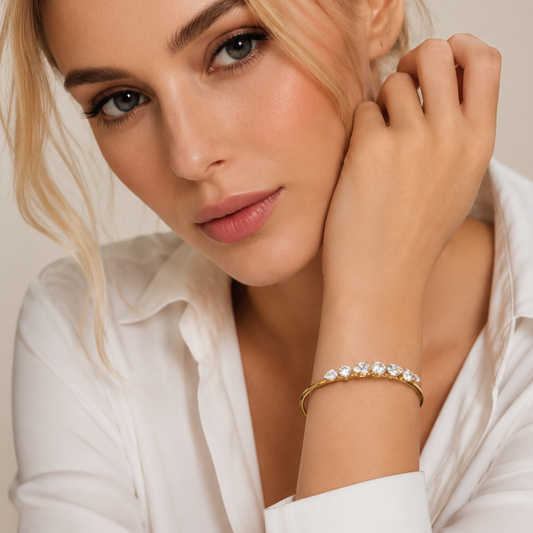 Aurelia tennis bracelet featuring sparkling clear stones on a gold-tone open cuff, styled elegantly on the wrist.