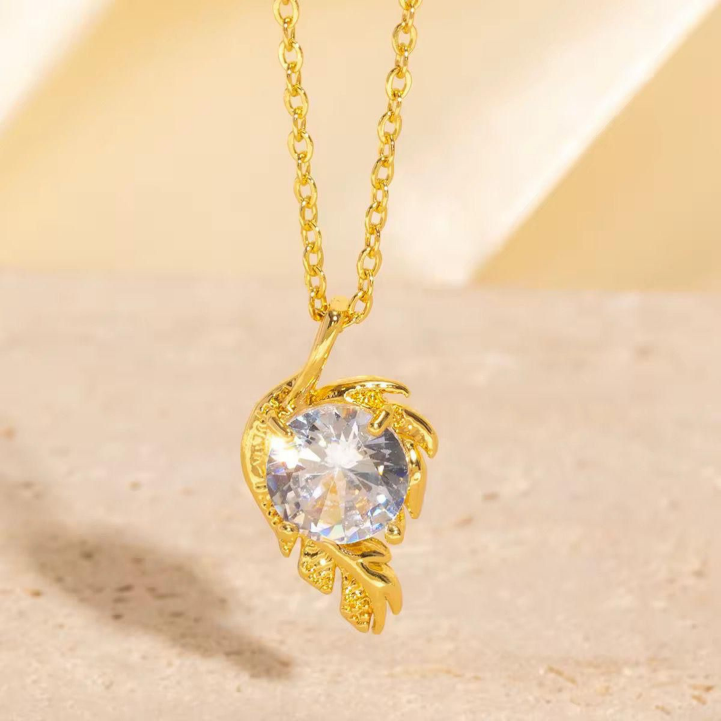 Gold solitaire necklace with a round clear stone in a sculpted floral pendant, shown on a delicate gold-tone chain by ZARIVA.