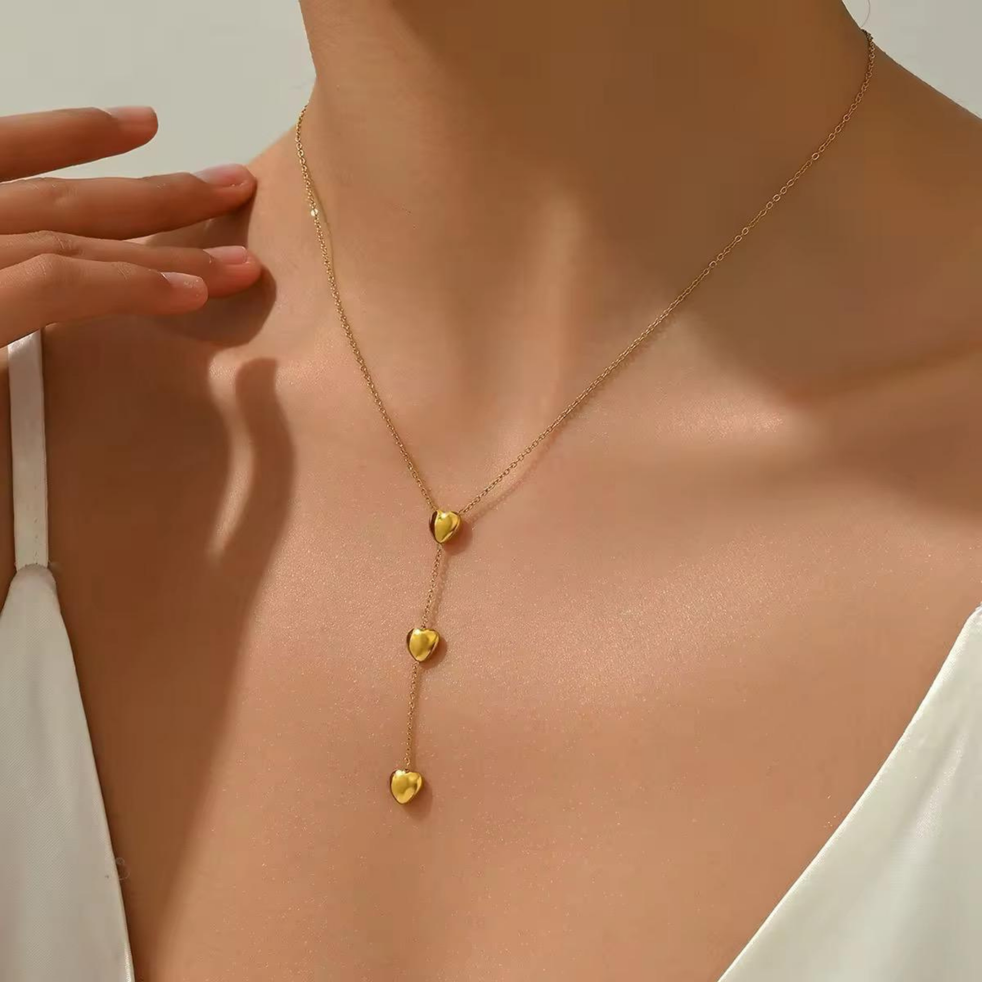 Amora Double Heart Lariat Necklace worn on a woman, showcasing its delicate gold chain and cascading heart pendant design.