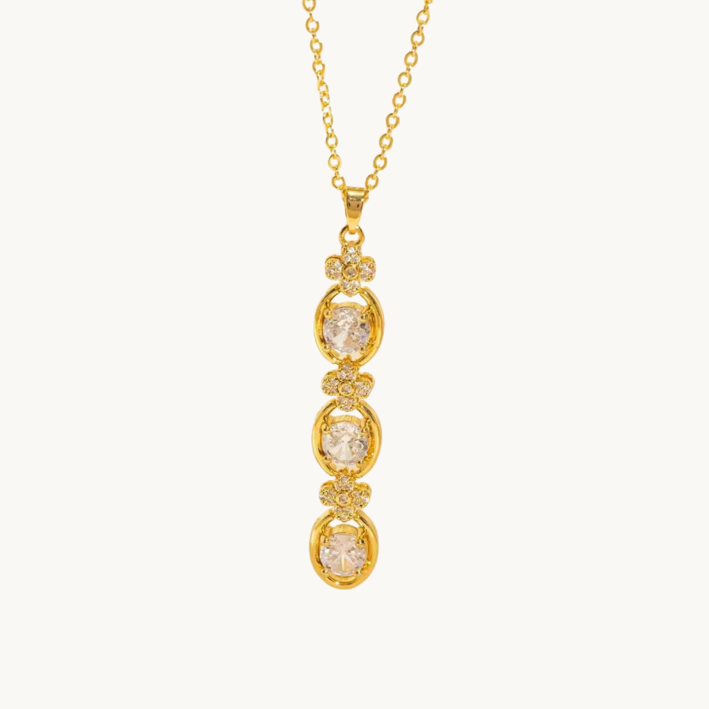 Aurelia Cascade Necklace showing its elongated cascading pendant with three round sparkling stones and delicate floral accents