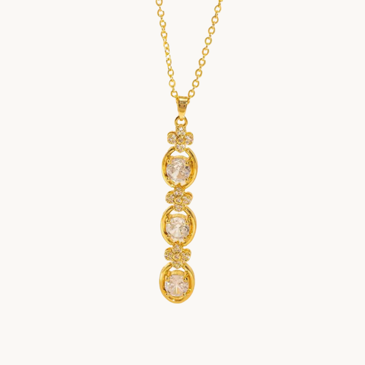 Aurelia Cascade Necklace showing its elongated cascading pendant with three round sparkling stones and delicate floral accents