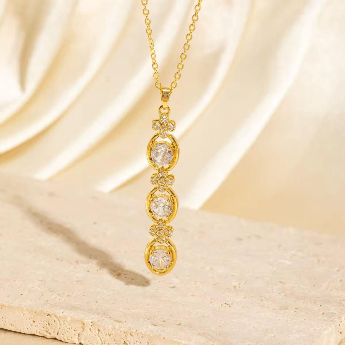 Aurelia Cascade Necklace featuring three sparkling round stones in a gold-tone cascading pendant with floral accents by ZARIVA