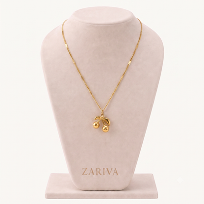 Cherry pendant necklace featuring a polished gold-tone double-cherry charm with curved leaf details on a delicate chain.