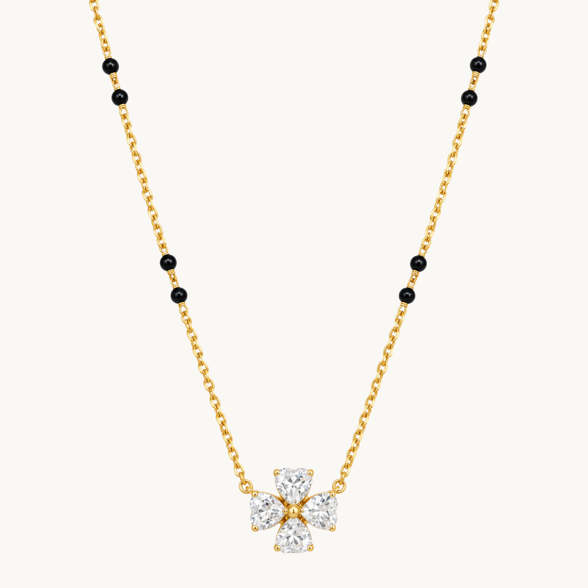 Gold mangalsutra necklace with black beads and a four-stone clear zircon flower pendant on a clean white background by ZARIVA.