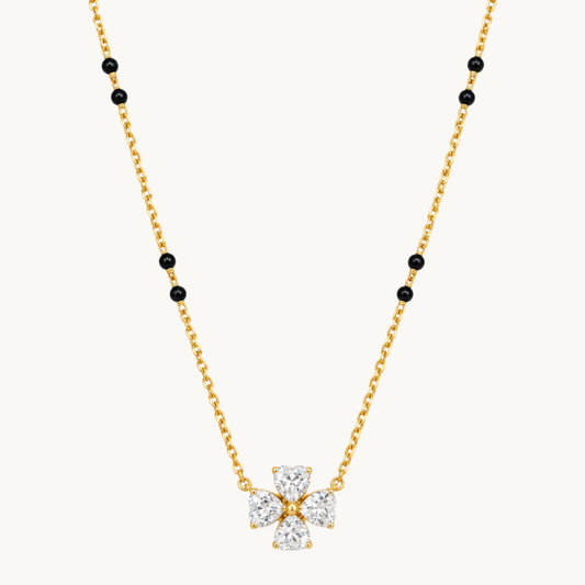 Gold mangalsutra necklace with black beads and a four-stone clear zircon flower pendant on a clean white background by ZARIVA.