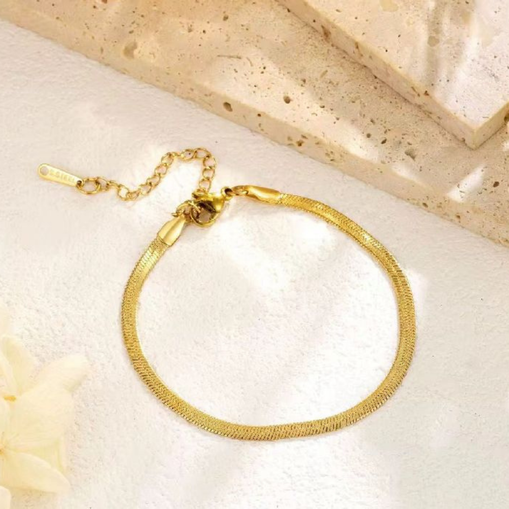 Gold herringbone bracelet featuring a flexible flat chain and polished gold finish, styled for an elegant everyday look