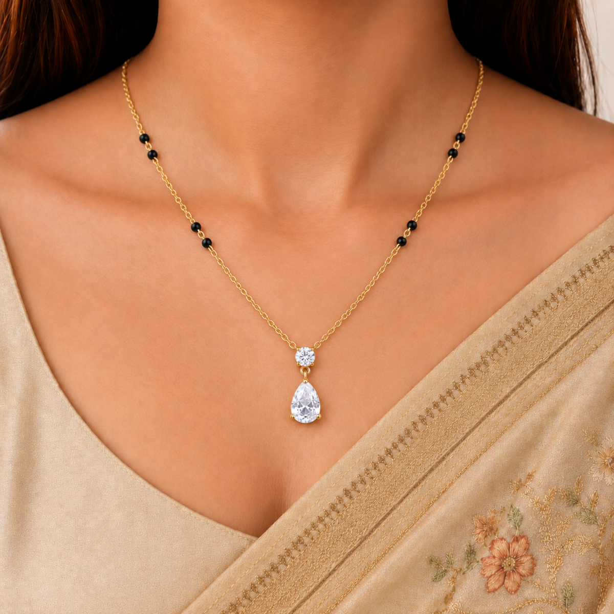Gold mangalsutra necklace with black beads, a round zircon and a teardrop pendant displayed on a ZARIVA jewellery bust.