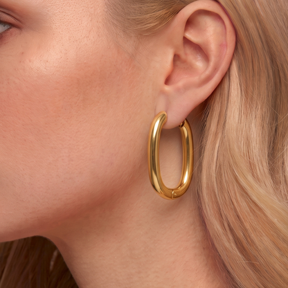 Gold oval hoop earrings worn on the ear, highlighting the elongated curved silhouette and polished contemporary design by ZARIVA.
