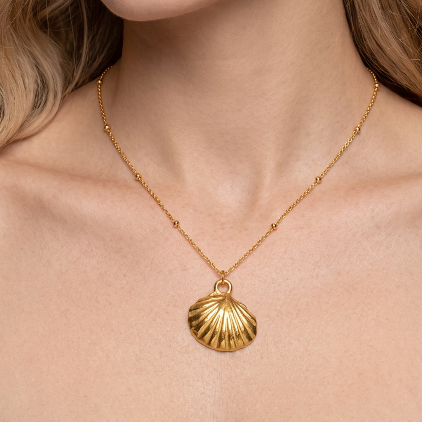 Gold seashell necklace for women shown worn at the neckline, highlighting its delicate chain and sculpted shell pendant