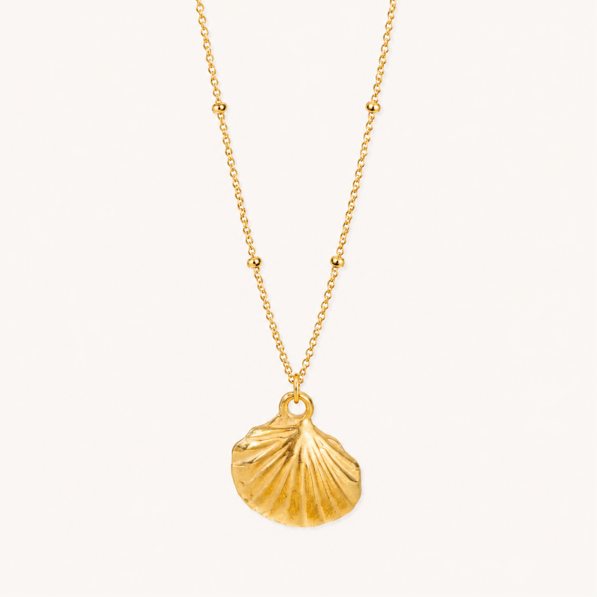 Gold seashell pendant necklace featuring a sculpted shell charm and delicate beaded chain, styled on a ZARIVA jewellery display