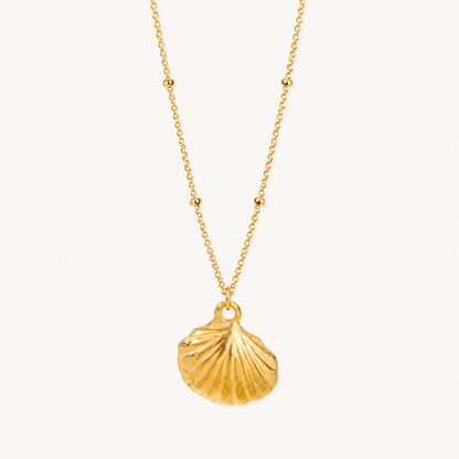 Gold seashell pendant necklace featuring a sculpted shell charm and delicate beaded chain, styled on a ZARIVA jewellery display
