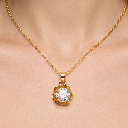 Gold solitaire necklace worn close to the neckline, showcasing its delicate chain and elegant floral pendant design.