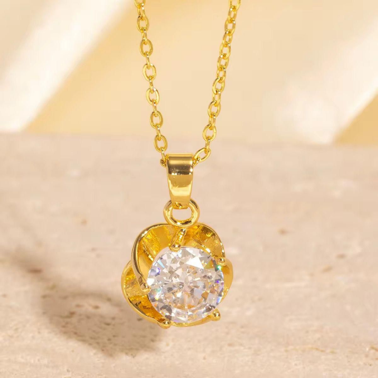 Gold solitaire necklace with a brilliant clear center stone and sculpted floral pendant design from ZARIVA.