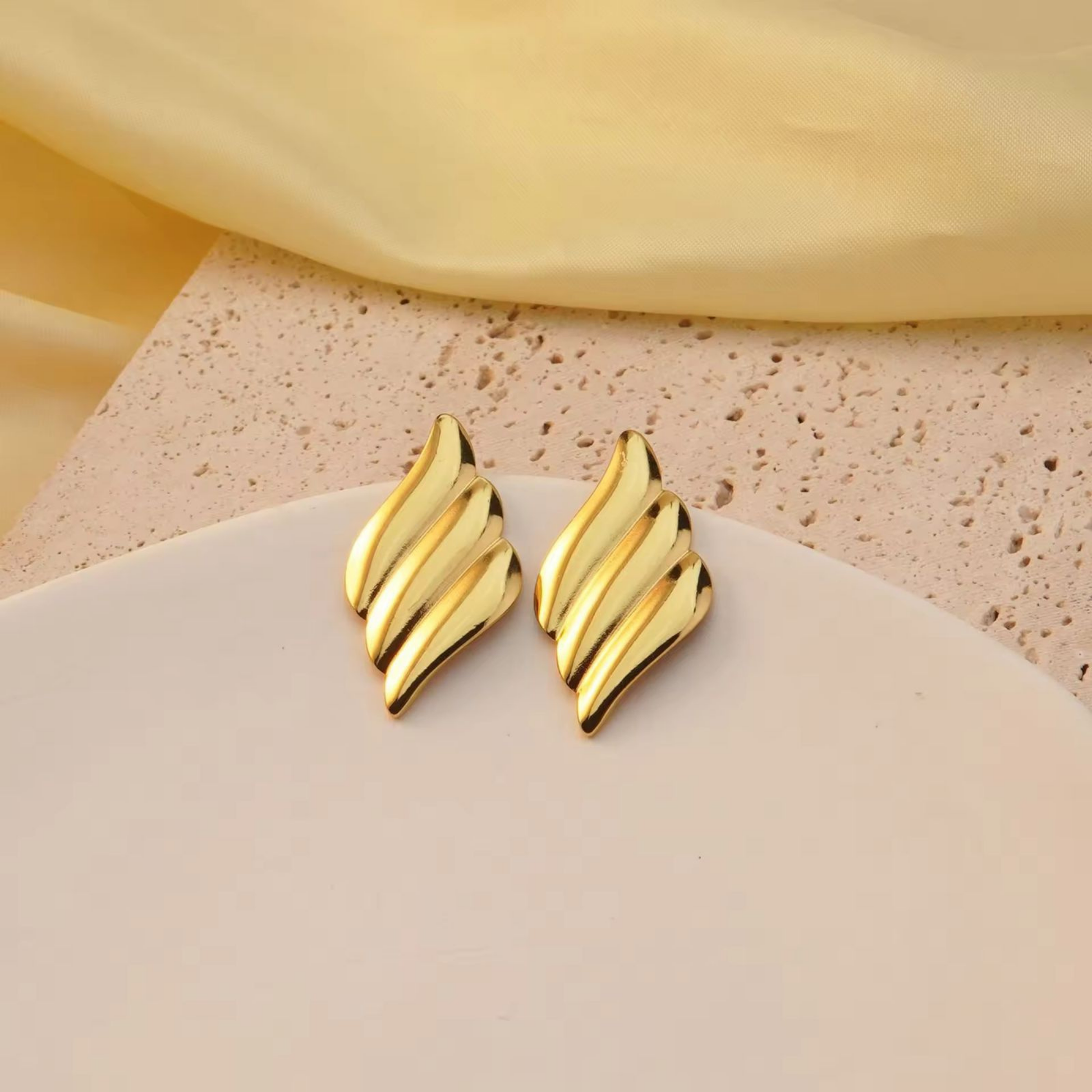 Gold statement earrings displayed in a refined setting, highlighting their sculptural polished design and contemporary elegance by ZARIVA.
