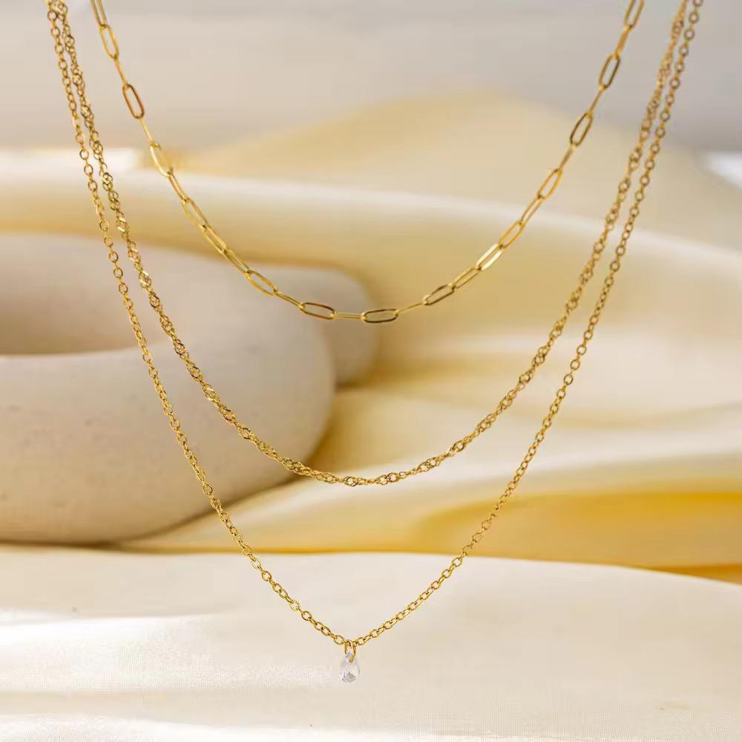 Layered gold necklace with a clear crystal charm styled on a soft neutral background, showcasing the Aurelia design by ZARIVA.