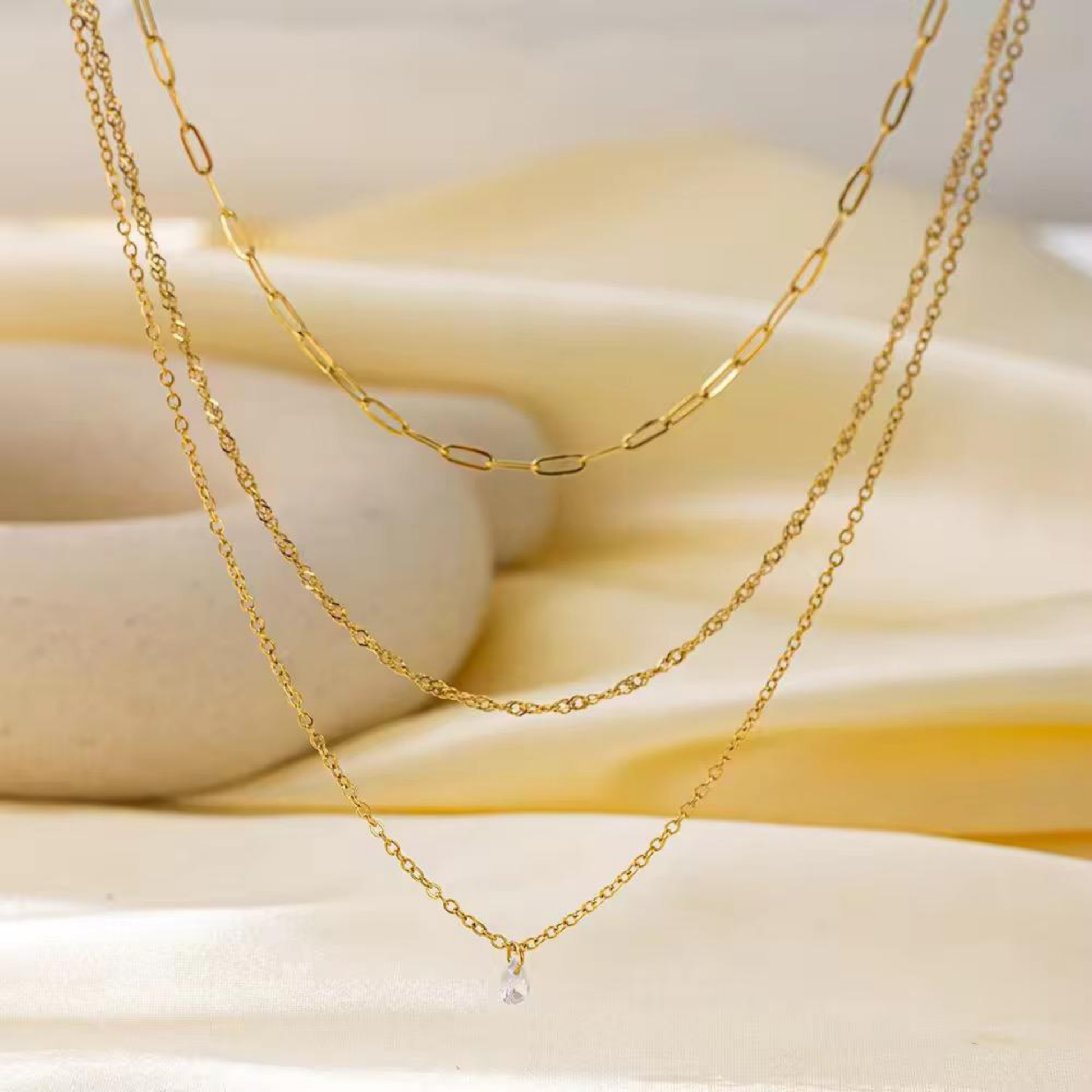 Layered gold necklace with a clear crystal charm styled on a soft neutral background, showcasing the Aurelia design by ZARIVA.
