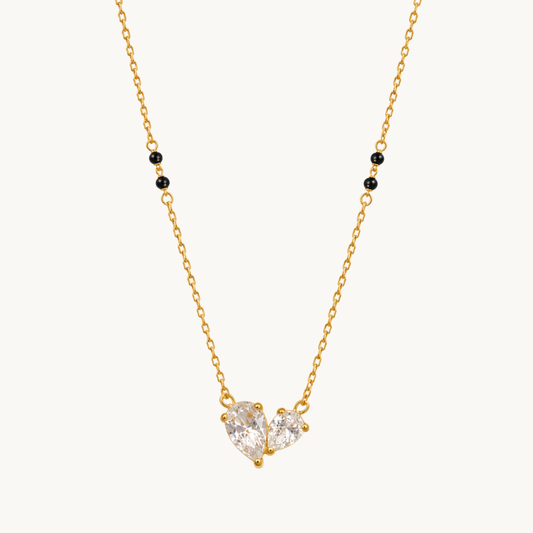 ZARIVA mangalsutra featuring a sparkling open heart pendant with faceted cubic zirconia stones and black beads.