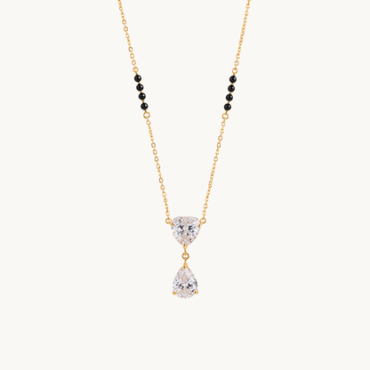 ZARIVA heart pendant mangalsutra with black beads, a gold-tone chain and sparkling teardrop stone on a clean background.