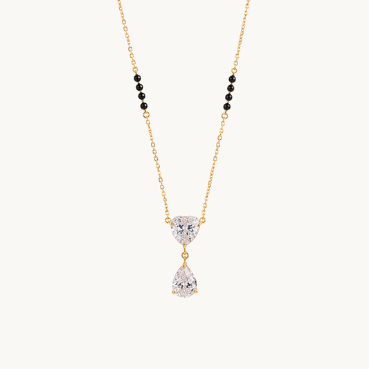 ZARIVA heart pendant mangalsutra with black beads, a gold-tone chain and sparkling teardrop stone on a clean background.