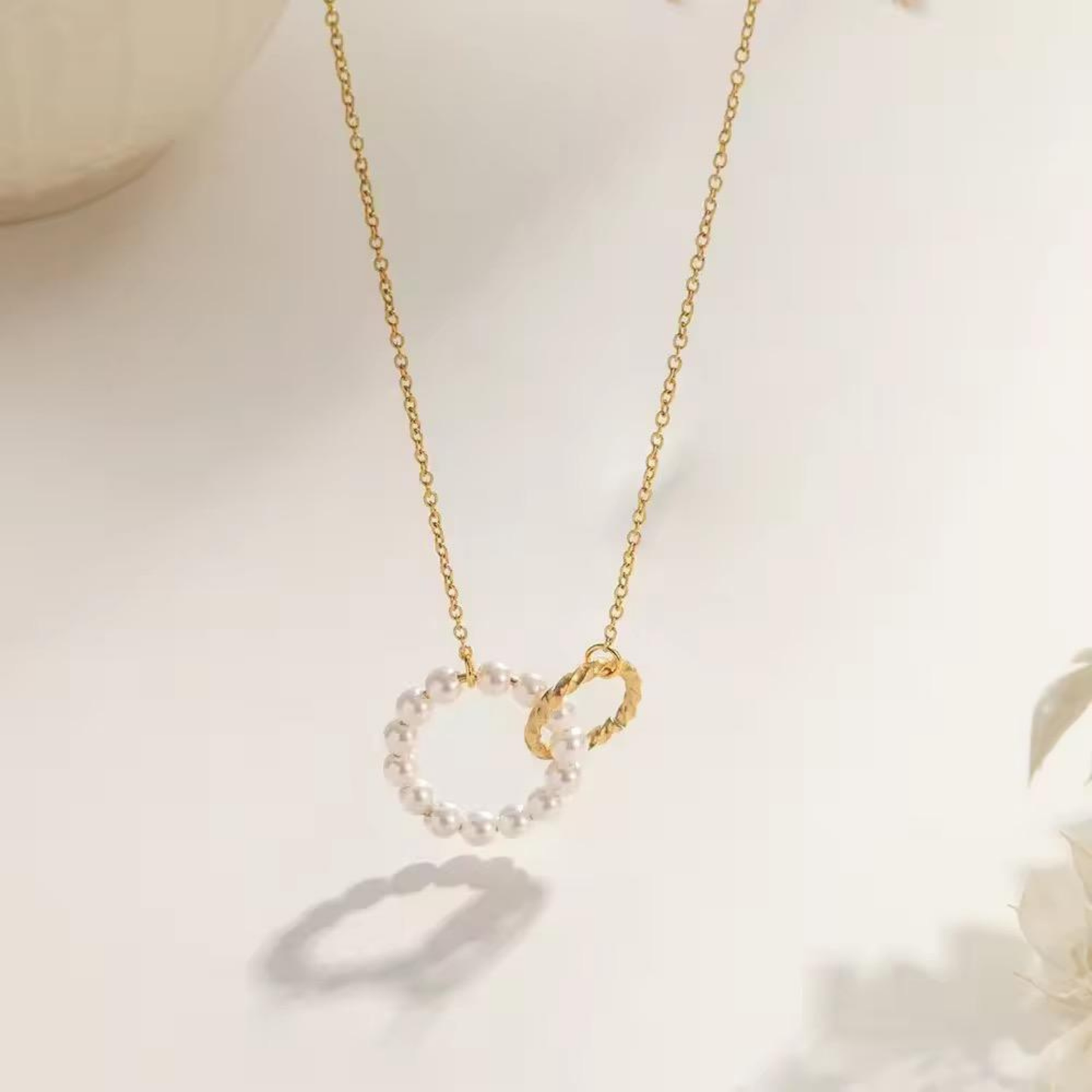 Pearl circle pendant necklace featuring a delicate white pearl circle paired with a textured gold-tone charm on a fine chain.
