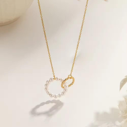 Pearl circle pendant necklace featuring a delicate white pearl circle paired with a textured gold-tone charm on a fine chain.