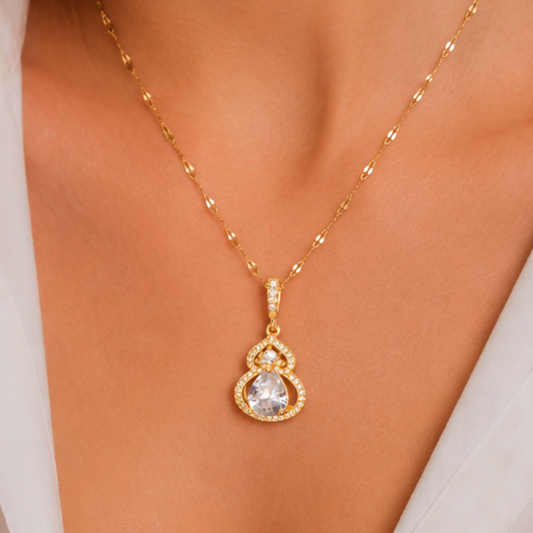 Teardrop pendant necklace featuring a large clear pear-cut stone, sparkling halo accents, and a gold-toned decorative chain.