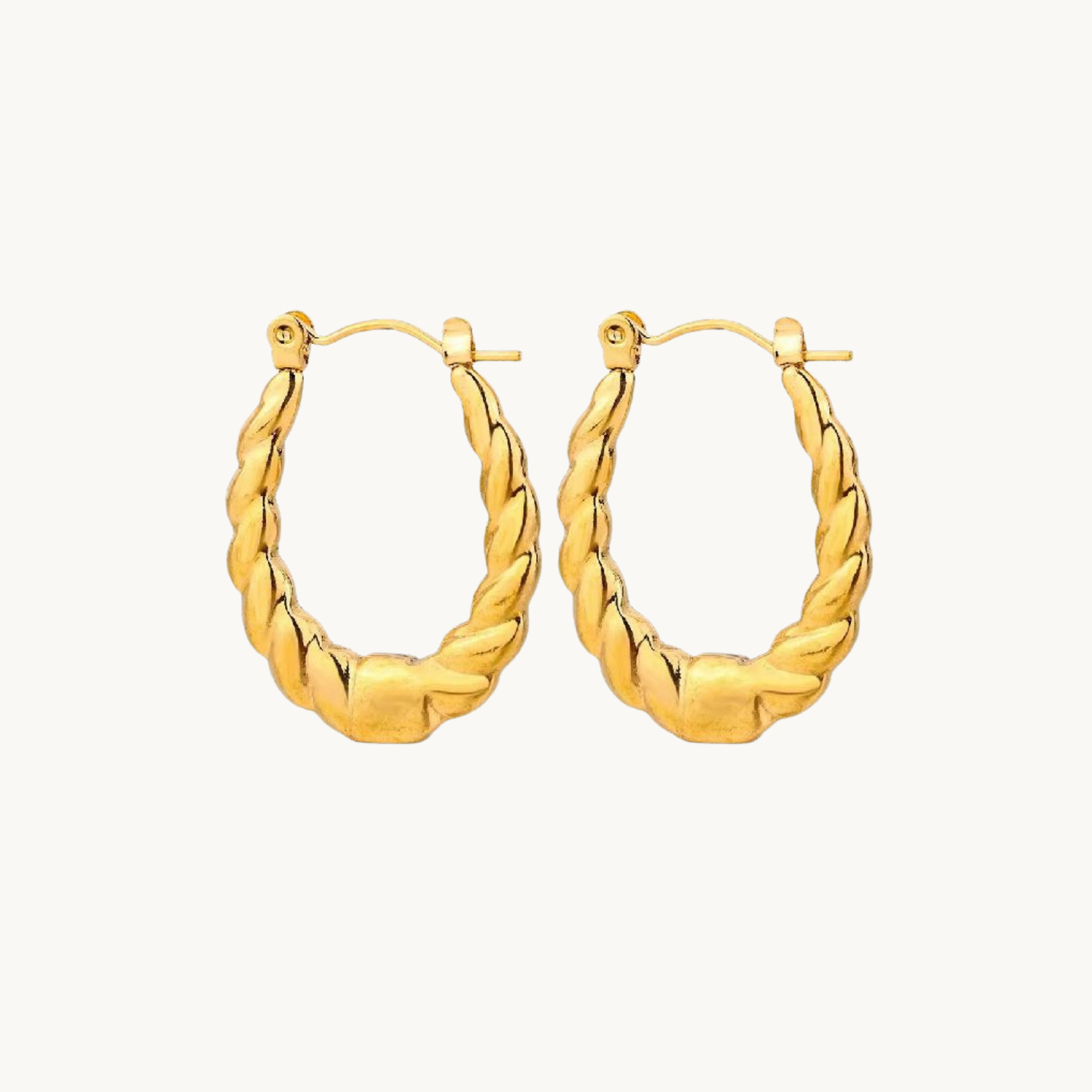 Vintage hoop earrings with a twisted rope-inspired texture, elongated shape and polished gold-tone finish styled by ZARIVA.