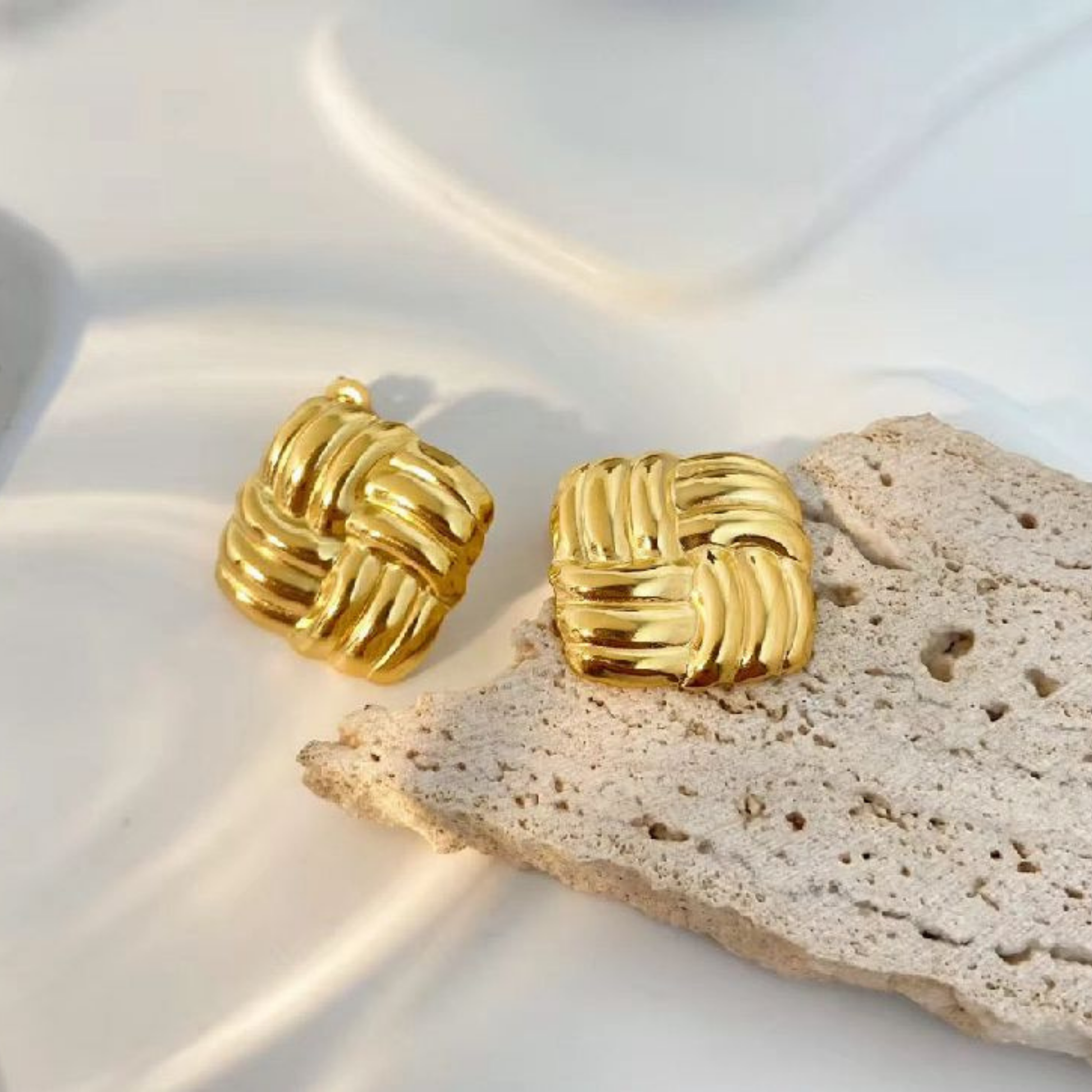 Woven knot earrings featuring layered textured bands and a polished gold-tone finish, styled as refined everyday jewellery.