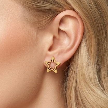Model wearing ZARIVA Astera Mini Star Stud Earrings. Small open star earrings under 1 cm crafted from SS316L stainless steel with 18K PVD gold plating for everyday luxury.