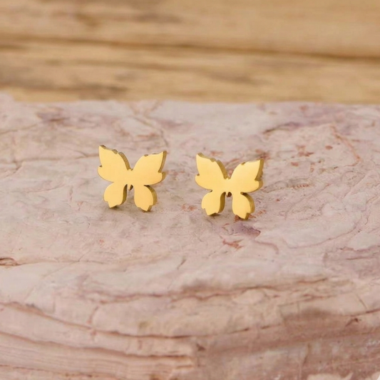 ZARIVA Mariposa Mini Butterfly Stud Earrings displayed on a natural stone surface. Premium SS316L stainless steel earrings with 18K PVD gold plating, anti-tarnish finish and elegant butterfly design.