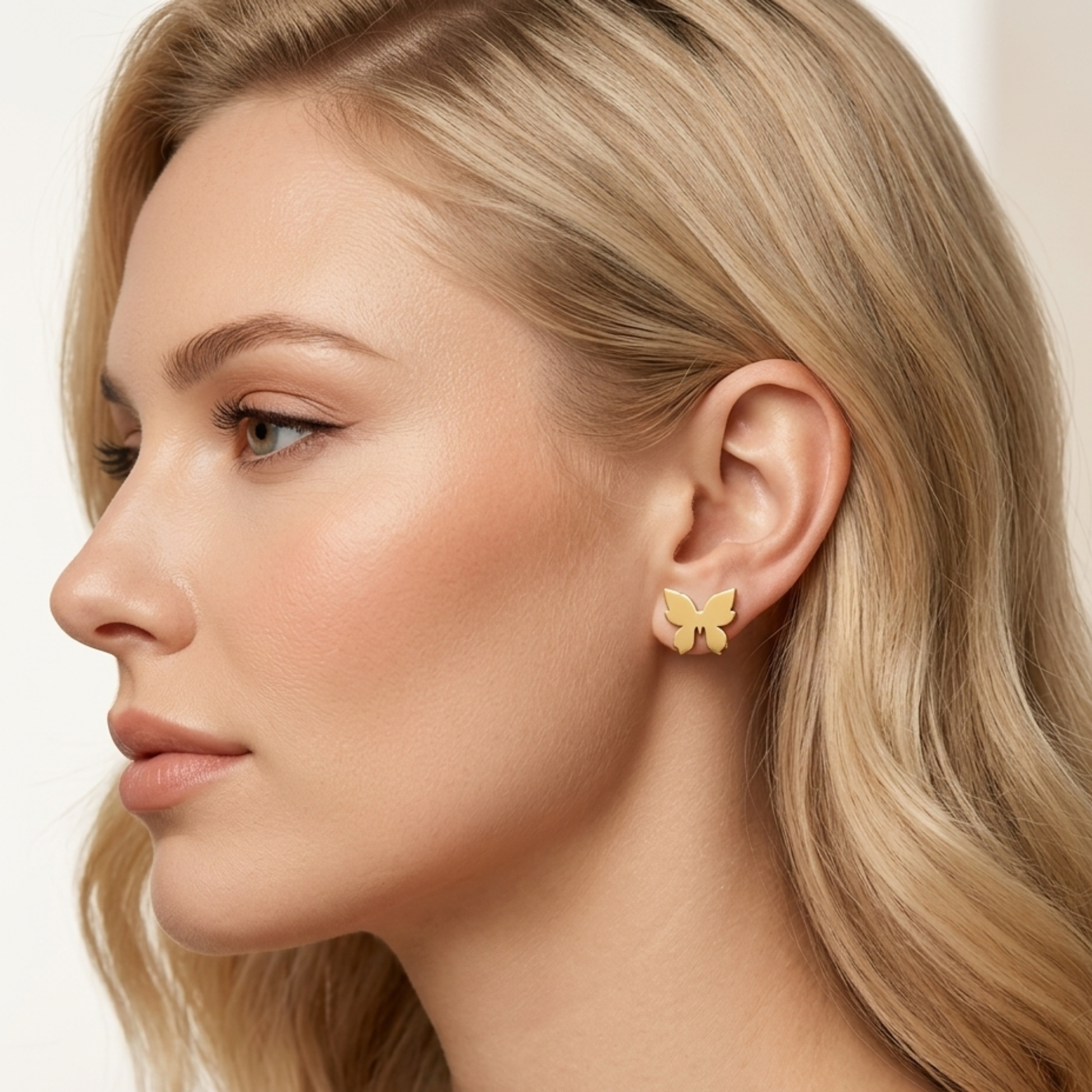 Model wearing ZARIVA Mariposa Mini Butterfly Stud Earrings. Elegant minimalist butterfly earrings crafted from SS316L stainless steel with durable 18K PVD gold plating for everyday wear.