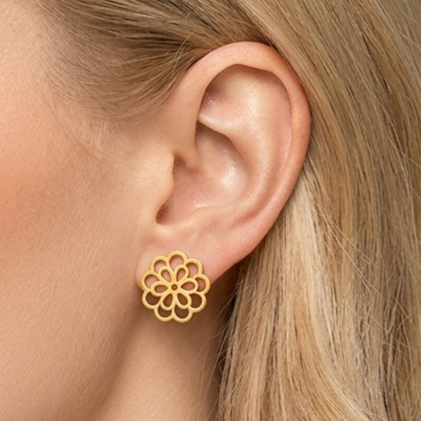 Close-up of ZARIVA Mini Floral Gold Stud Earrings being worn on the ear. Small under 1 cm flower earrings made from SS316L stainless steel with 18K PVD gold plating for everyday luxury.