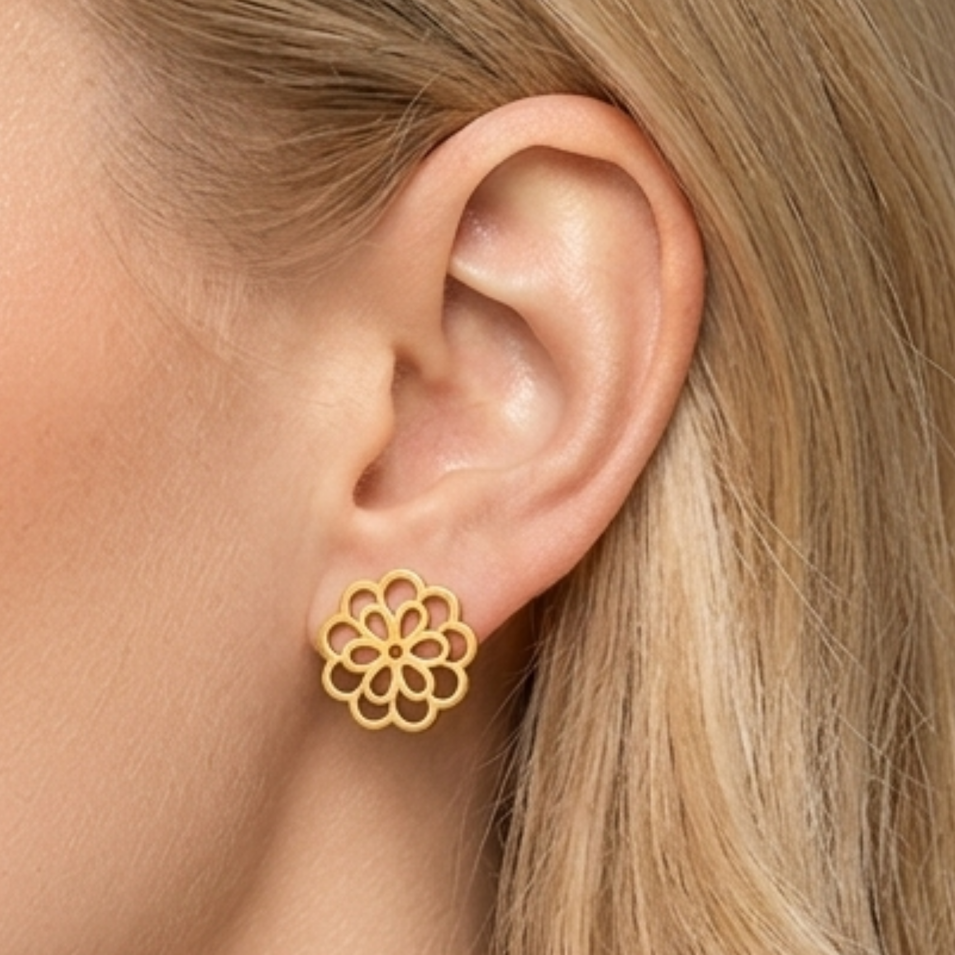 Close-up of ZARIVA Mini Floral Gold Stud Earrings being worn on the ear. Small under 1 cm flower earrings made from SS316L stainless steel with 18K PVD gold plating for everyday luxury.