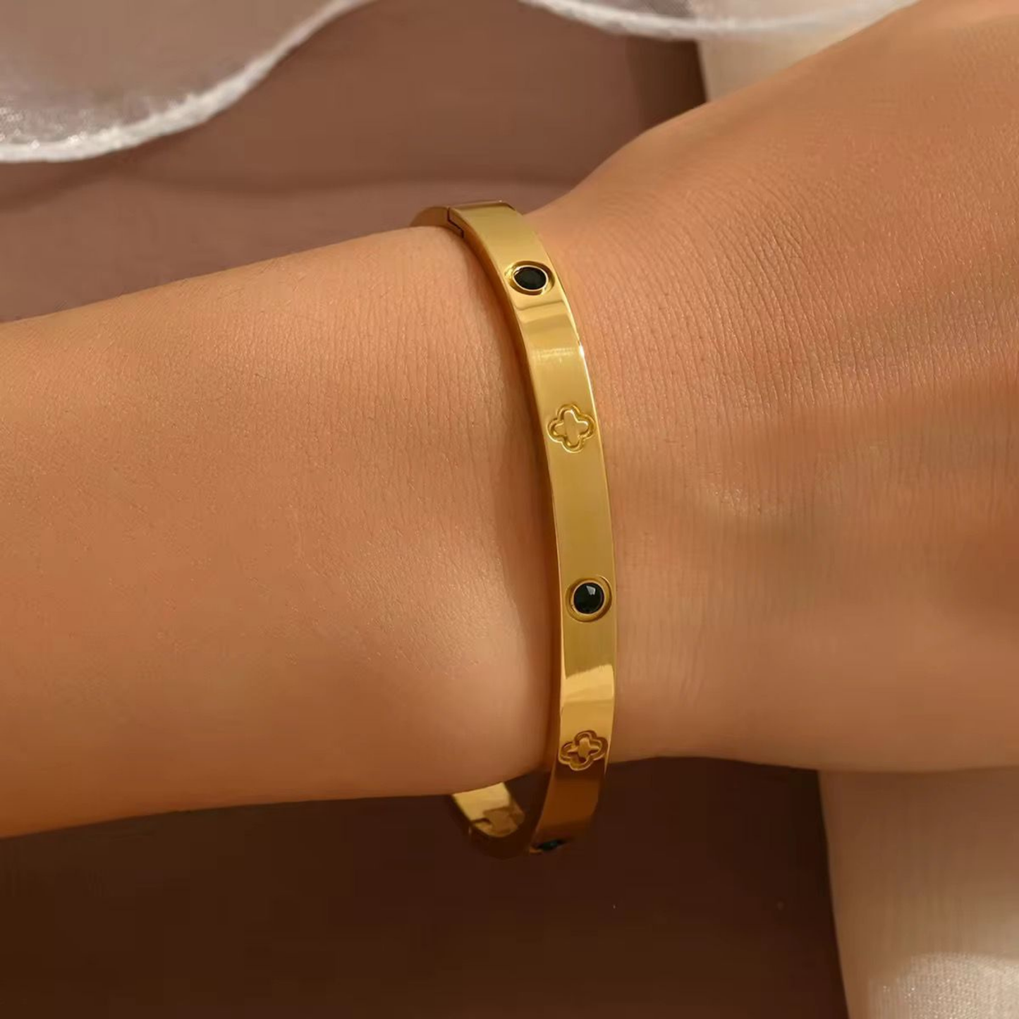 Zariva Noir Clover Luxe Bangle in 18K Gold PVD plated SS316L stainless steel featuring black onyx-inspired accents and signature clover motifs. Anti-tarnish, water-resistant, hypoallergenic everyday luxury bangle for women.