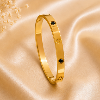 Zariva Noir Clover Luxe Bangle in 18K Gold PVD plated SS316L stainless steel featuring black onyx-inspired accents and signature clover motifs. Anti-tarnish, water-resistant, hypoallergenic everyday luxury bangle for women.