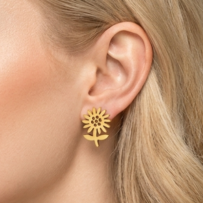 Close-up of ZARIVA Soleia Bloom Mini Floral Stud Earrings worn on the ear. Small sunflower-inspired gold stud earrings under 1 cm made from SS316L stainless steel with 18K PVD gold plating.